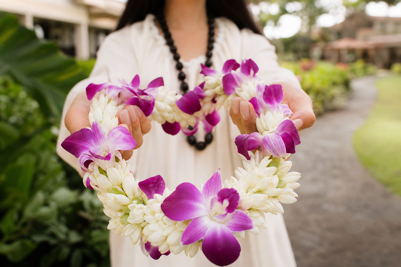 A single flower lei placed gently across open hands, a quiet gesture of welcome