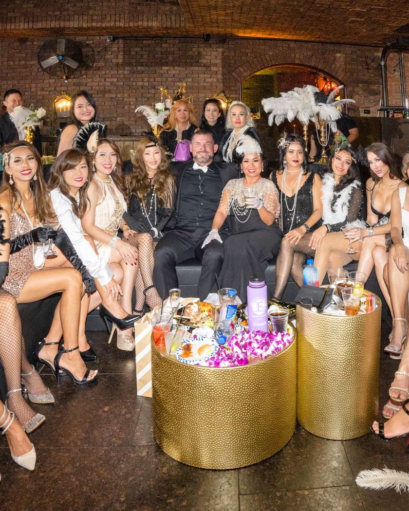 Guests in 1920s attire seated around gold tables at a Great Gatsby soirée produced by JJ Signature Experiences