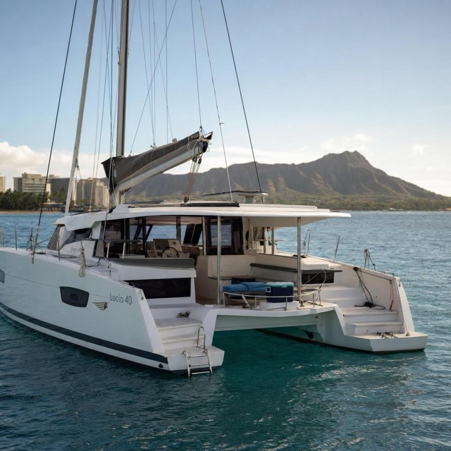 White sailing catamaran anchored in turquoise water off Oʻahu